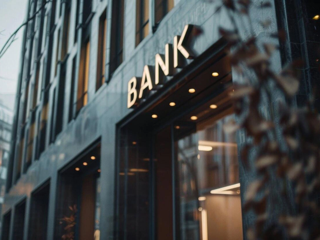 Osvetljen napis »Bank« nad vhodom v bančno poslovalnico