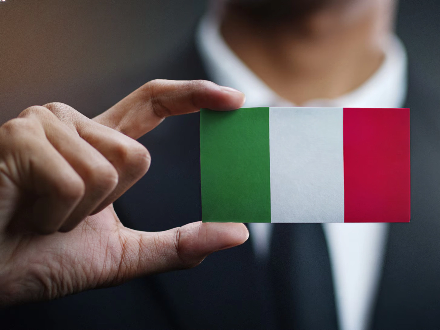 Poslovnež v roki drži kartico z italijansko zastavo