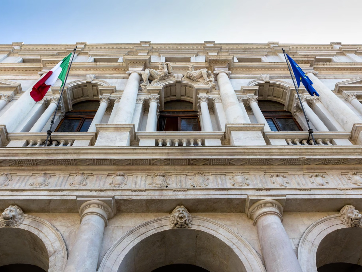 Pročelje zgodovinske palače z italijansko zastavo in zastavo Evropske unije